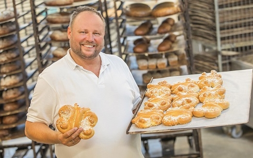 INTERSPAR Bäcker mit Backblech, auf dem viele Brioche-Schmetterlinge liegen